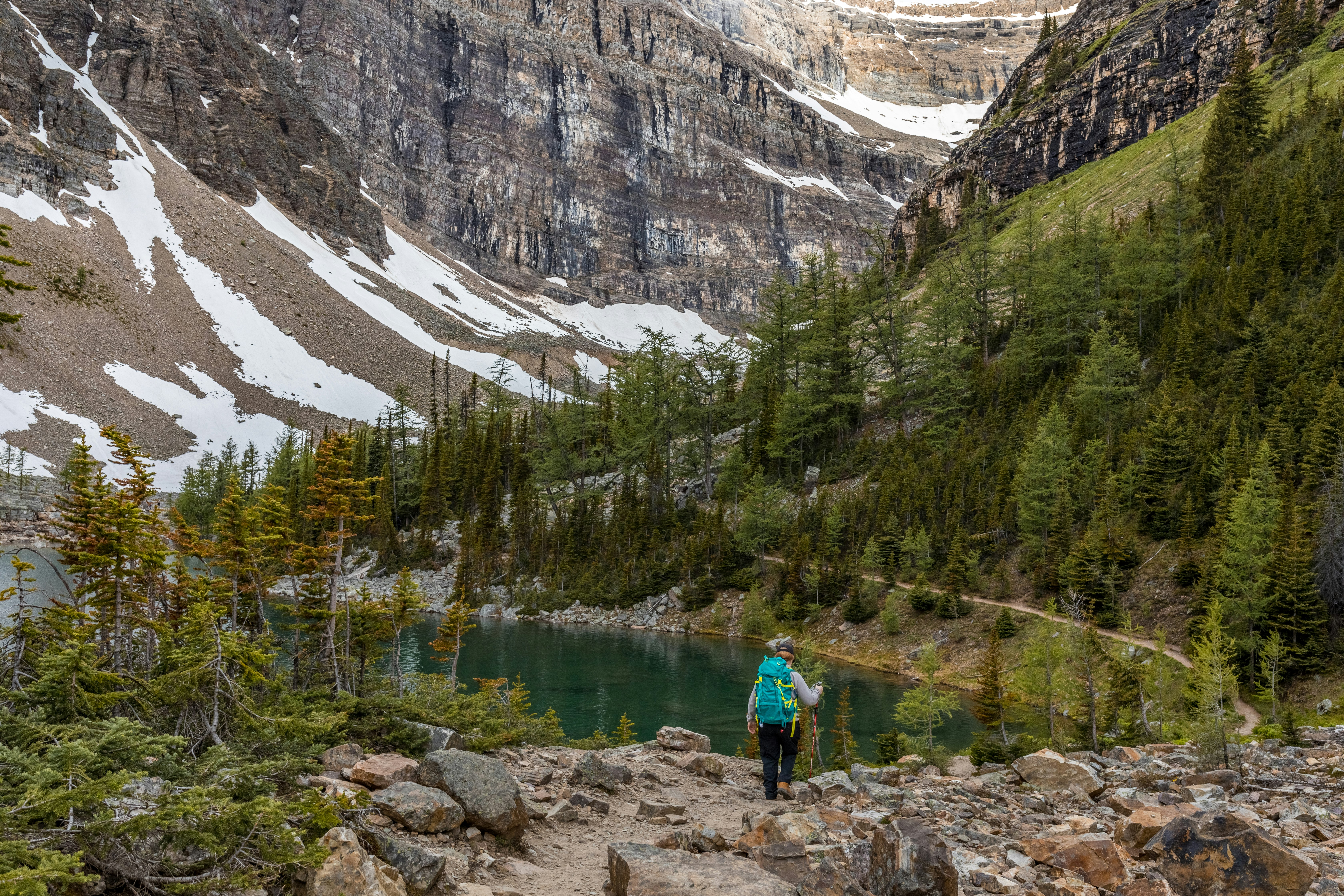 man in blue shirt and blue backpack standing on rock near river during daytime